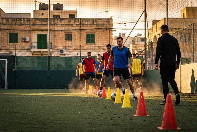 Players of several nationalities running a cone drill at golden hour