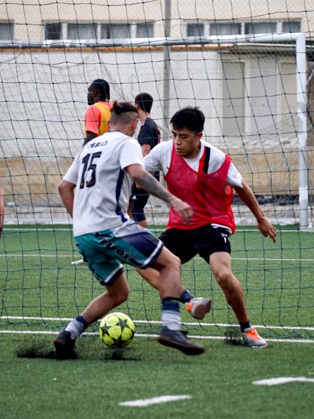 Two players closing each other down in front of the goal during an open play